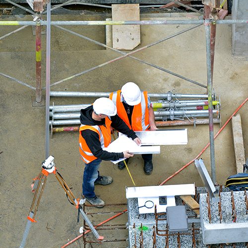 Aerial view of two unrecognized civil engineers inspecting construction site. Building development concept.