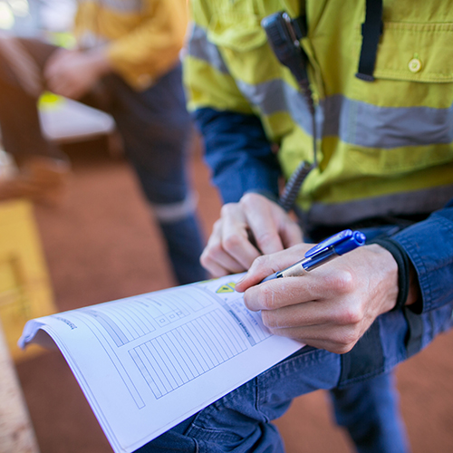 Construction coal miner supervisor conducting safety checking on job hazards analysis on hot work permit before sign off approval to work on open field construction coal mine site Sydney, Australia