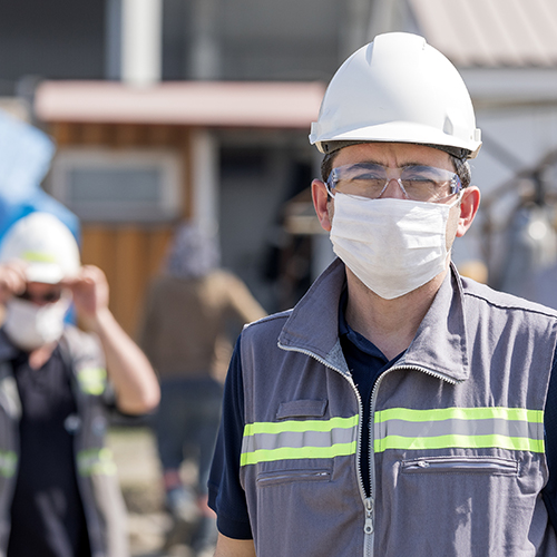 The worker staff or engineer protects himself from covid-19 coronavirus with a protective mask in the construction site.